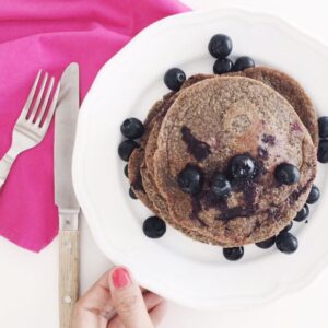 Banana blueberry pancakes with more blueberries and some maple syrup on top