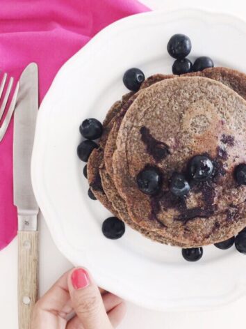 Banana blueberry pancakes with more blueberries and some maple syrup on top